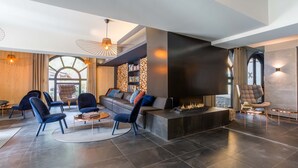 A modern living room with a fireplace, dark tiled flooring, and contemporary furniture.