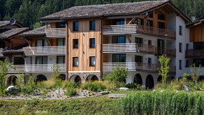 A multi-story hotel with wooden balconies, arched windows, and a view of a lake.