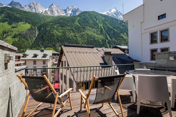 A terrace with two chairs, overlooking a mountainous landscape with buildings in the foreground.