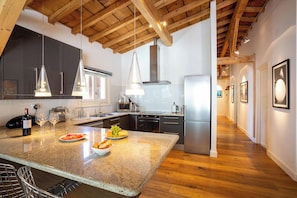 A modern kitchen with a central island, stainless steel appliances, and pendant lighting.