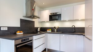Een moderne keuken met witte kasten, een inbouwoven en een roestvrijstalen afzuigkap.