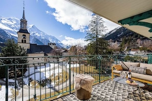 Un balcon avec vue sur une église et des montagnes enneigées.