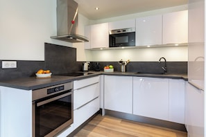 Una cocina moderna con horno integrado, microondas y extractor de acero inoxidable.