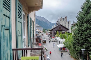 A street view with buildings, a mountain in the background, and a person walking.