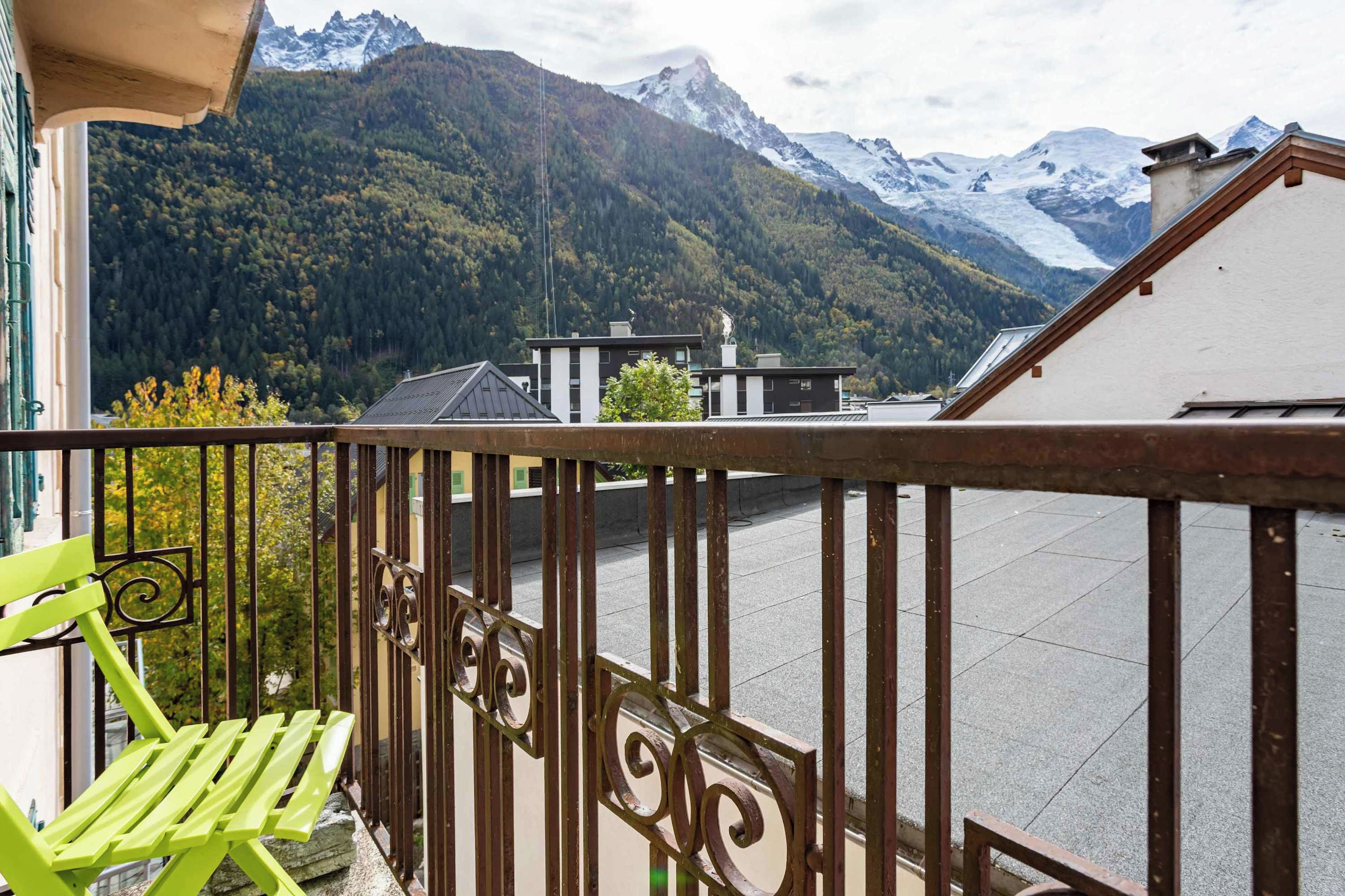 Een balkon met uitzicht op een bergketen en een meer.