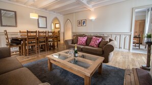Amplia sala de estar con una mesa de centro de madera, un sofá marrón y un comedor con sillas y mesa de madera.