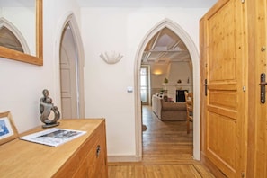 A hallway with wooden flooring, a wooden dresser, a framed picture, and a wooden door.