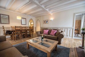 Amplia sala de estar con una mesa de centro de madera, un sofá con cojines estampados y un comedor con sillas y mesa de madera.