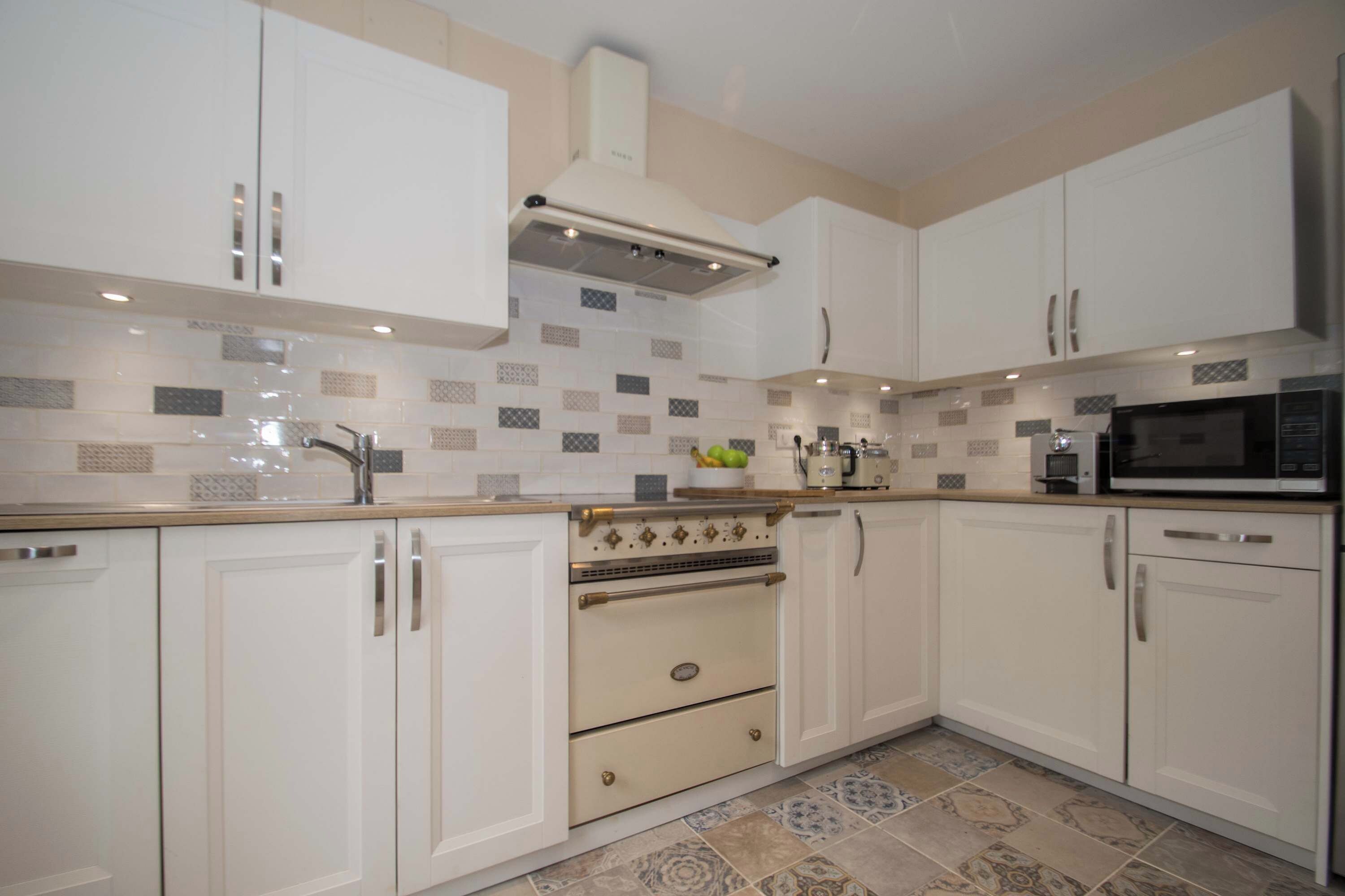 A modern kitchen with white cabinets, a built-in oven, and a microwave.