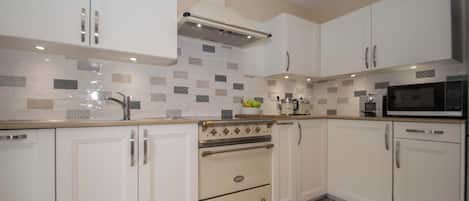 Una cocina moderna con armarios blancos, horno empotrado y microondas.