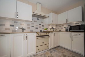 Una cocina moderna con armarios blancos, horno empotrado y microondas.