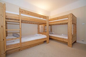 Una habitación con dos literas, cada una con una escalera, y un ventanal pequeño.