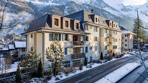 Ein mehrstöckiges Hotel mit Balkonen vor einer verschneiten Berglandschaft.