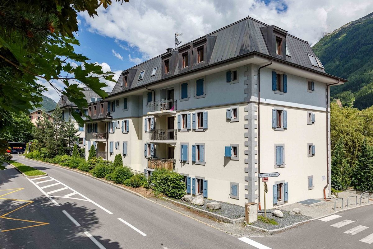 A multi-story building with balconies, a clear sky, and a road with a pedestrian crossing.