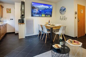 A modern kitchen with a TV mounted above the counter, a coffee machine, and a small refrigerator.