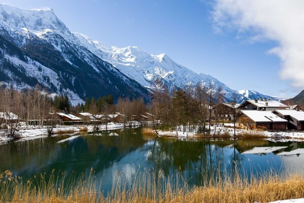 A mountain landscape with a lake, snow-covered houses, and clear skies.