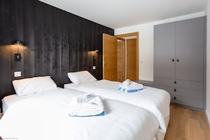 A hotel room with two beds, a wardrobe, and a wooden door.