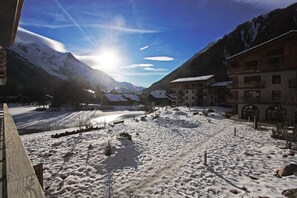 A snow-covered landscape with buildings and mountains in the background. - La Cordee 612 Apt, Lakefront, Chamonix All Year (Les Praz)