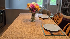 A kitchen with granite countertops, a vase of flowers, and a dining table set for two. - Cozy N. Raleigh Apt. with Pool and Hot Tub. Pets welcome BBQ Grill, TV & movies (Raleigh)