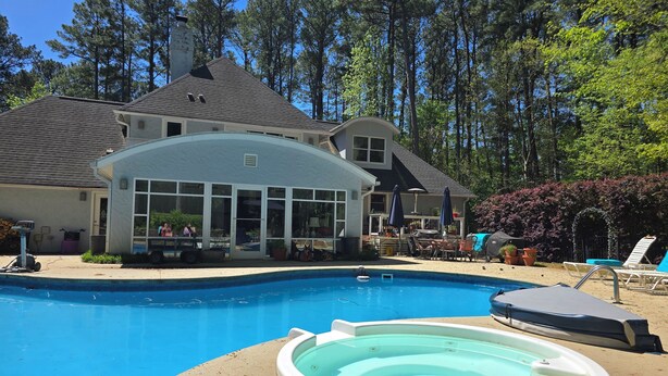 A swimming pool with a hot tub, surrounded by a deck area with lounge chairs and umbrellas. - Cozy N. Raleigh Apt. with Pool and Hot Tub. Pets welcome BBQ Grill, TV & movies (Raleigh)