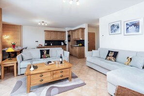 Een moderne woonkamer met een bank, salontafel en een eethoek met een lamp.