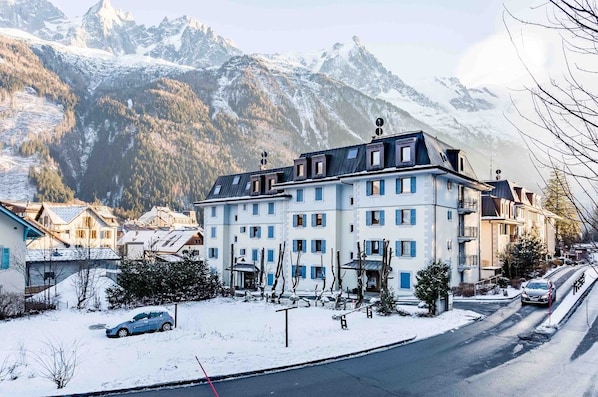 Un hôtel à plusieurs étages, avec un paysage enneigé et des montagnes en arrière-plan.