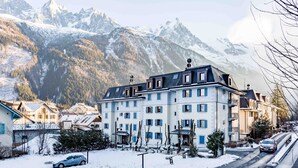 A multi-story hotel with a modern design, located in a snowy mountainous area with a view of snow-covered peaks.