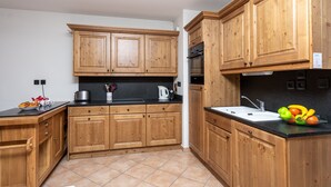 A kitchen with wooden cabinets, a black countertop, and a sink. There is a fruit bowl on the countertop.