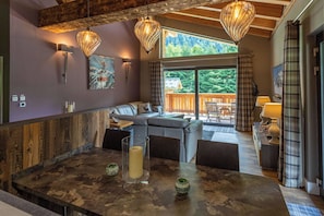 Eine moderne Küche mit einer großen Kochinsel, einem Essbereich mit Tisch und Stühlen sowie einer Sitzecke mit Sofa und Fernseher.