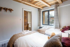 Une chambre d’hôtel avec deux lits, un plafond en bois, une fenêtre avec des rideaux et une vue sur une maison à l’extérieur.