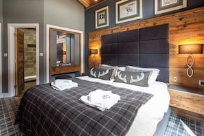 Ein Hotelzimmer mit einem großen Bett, einem hölzernen Kopfteil, einem Spiegel und einer Wandlampe.