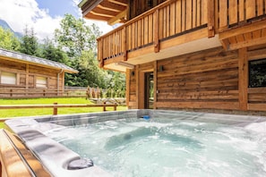 Una cabaña de madera con jacuzzi y balcón.