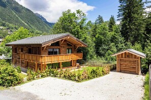 Eine Holzhütte mit Balkon, überdachter Veranda und separater Garage.