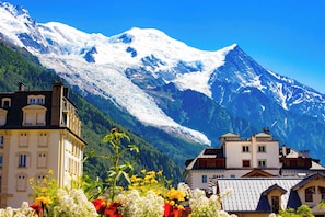 Eine Berglandschaft mit schneebedeckten Gipfeln und einem Tal mit Gebäuden.