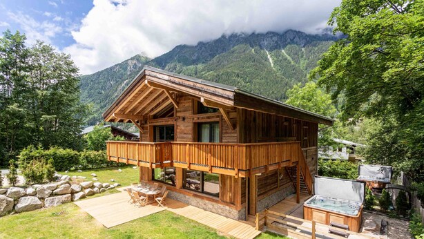 Une cabane en bois dotée d’une terrasse, d’un bain à remous et offrant une vue sur les montagnes.