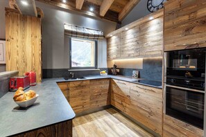 A modern kitchen with wooden cabinetry, a built-in oven, and a window with a view of the outdoors.