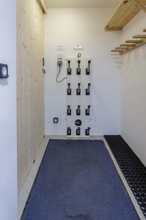 A room with a door equipped with multiple locks and a control panel, a wooden wall, and a textured mat on the floor.