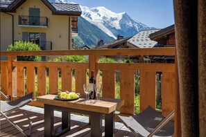 A wooden deck with a table set for a meal, a bottle of wine, and glasses. - Coin des Drus appt, Golfing, - Chamonix All Year (Les Praz)