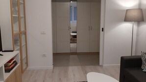 Ett rum med en garderob, en lampa, en soffa och en bokhylla.