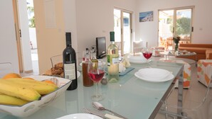 Un comedor con una mesa de vidrio, platos, cubiertos y botellas de vino.