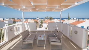 Un espacio de estar techado al aire libre con vista al mar y edificios.