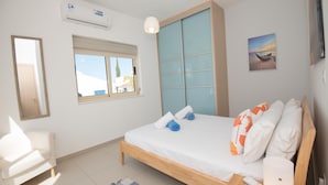 Un dormitorio con cama, mesita de noche, lámpara, ventana y aire acondicionado.