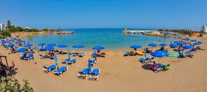 A beach with numerous blue umbrellas and sun loungers arranged in rows. - Cosy Pernera Villa, Private Pool, 8 mins Beach (Paralimni)
