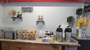 Una encimera de cocina con un tostador, un microondas, una cafetera y una bandeja con bagels.