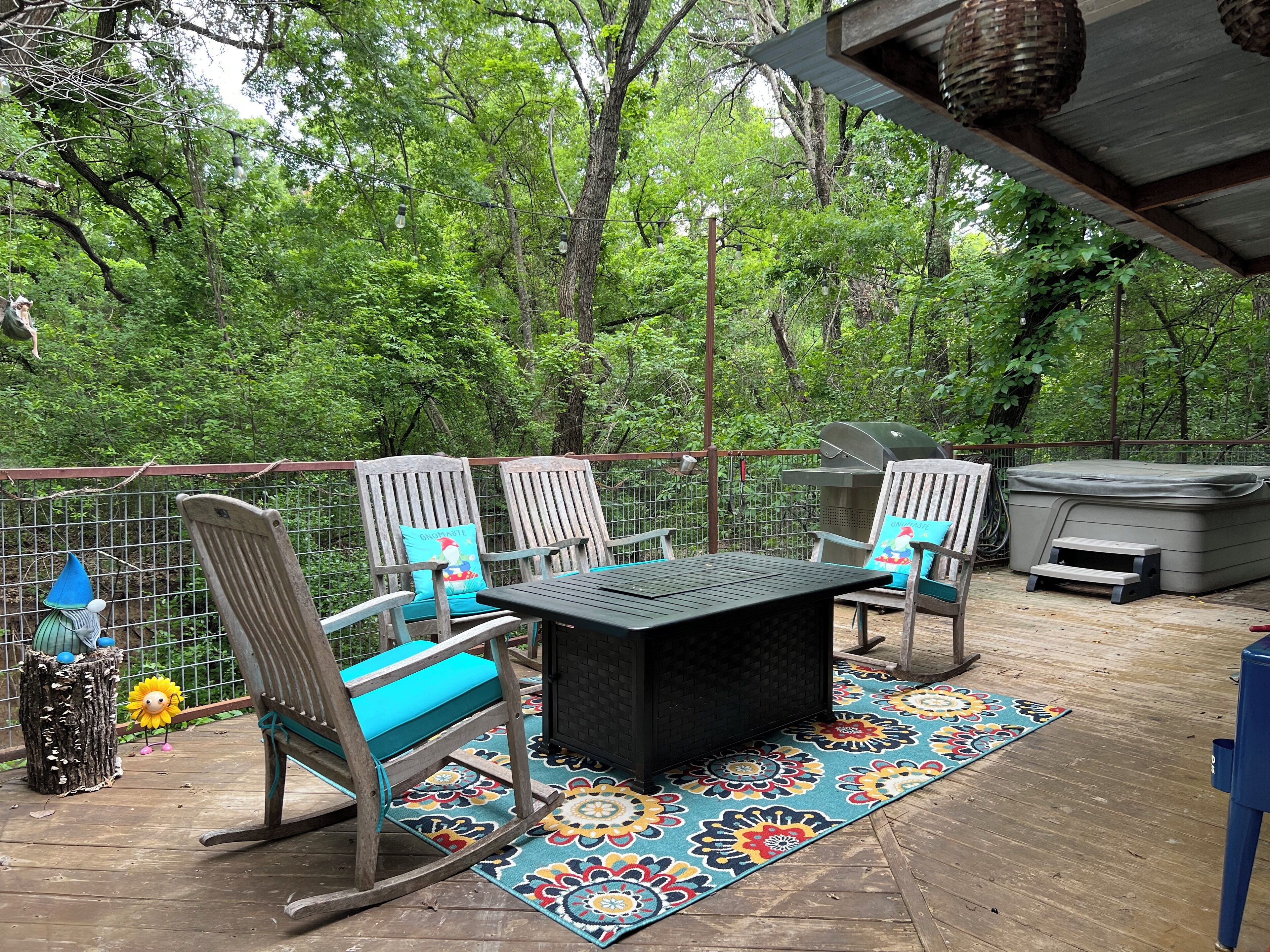 An outdoor patio with a table and chairs, surrounded by a wooden fence and lush greenery.