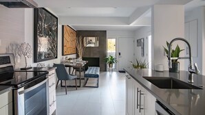 A modern kitchen with a dining area, stainless steel appliances, and a large window. - High-Spec Opulent Townhouse in Oak Lawn (Dallas)