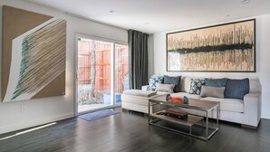 A modern living room with a sofa, coffee table, and artwork. - High-Spec Opulent Townhouse in Oak Lawn (Dallas)