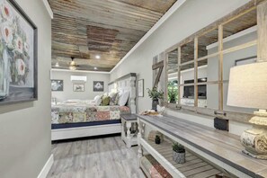 A bedroom with a bed, a dresser, a mirror, and a ceiling with exposed beams. - Luxury Cabin Hot-Tub & GameRoom-Wheelchair Access! (Fredericksburg)
