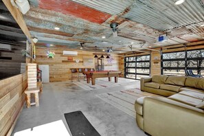 Um interior rústico com parede de madeira, mesa de bilhar, sofá e área de bar.