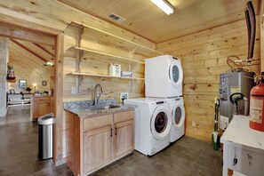 A compact kitchen with a washing machine, a sink, and a fire extinguisher. - Luxury Cabin Hot-Tub & GameRoom-Wheelchair Access! (Fredericksburg)